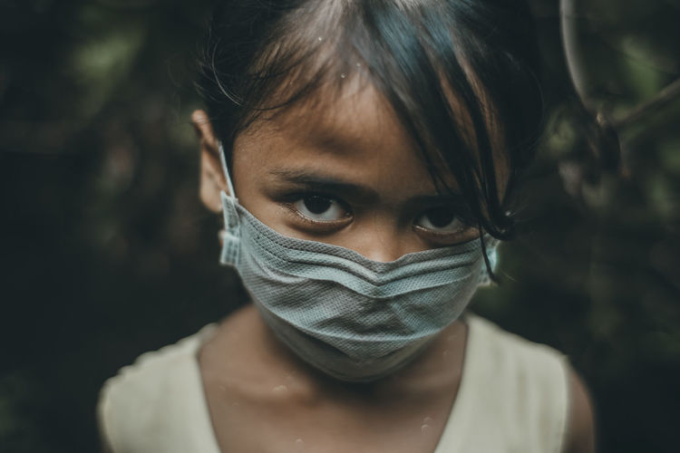 Close-up portrait of girl wearing mask standing outdoors