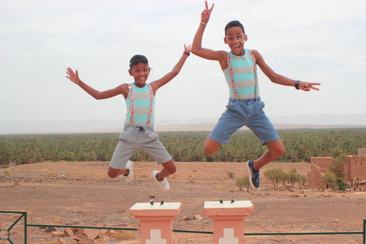 Portrait of boys jumping against field