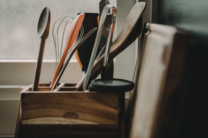 Close-up of kitchen utensils in wooden container at home