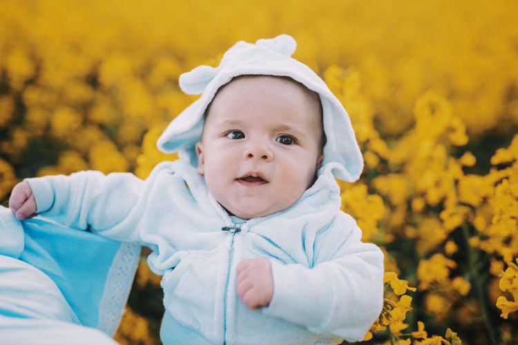 Close-up of cute baby boy against yellow flowering plants
