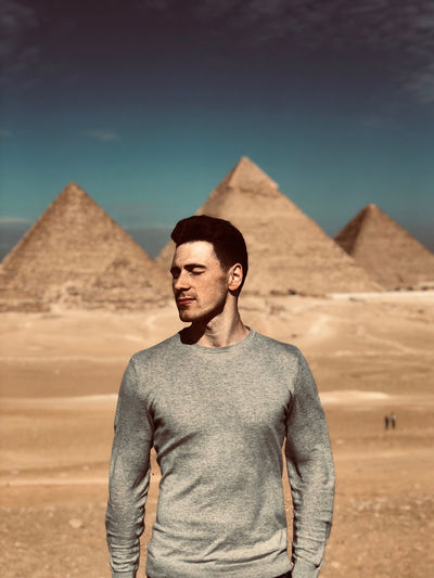 Young man standing in desert against sky