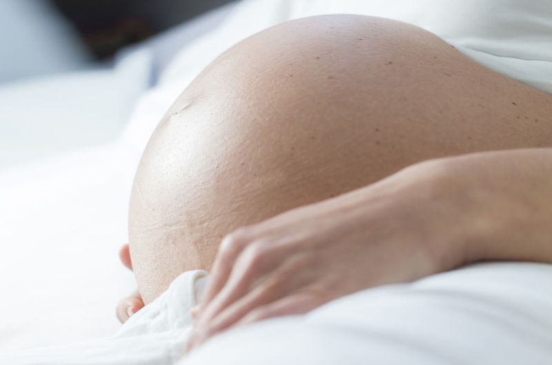 Close-up midsection of pregnant woman lying on bed