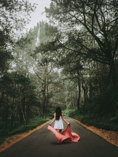 Woman walking on road amidst trees