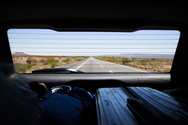 Road seen through rear windshield of car