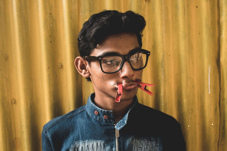Young man with clothespins on mouth