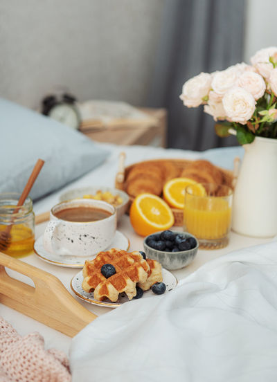 Romantic breakfast with coffee, waffles, orange juice and rose flowers.