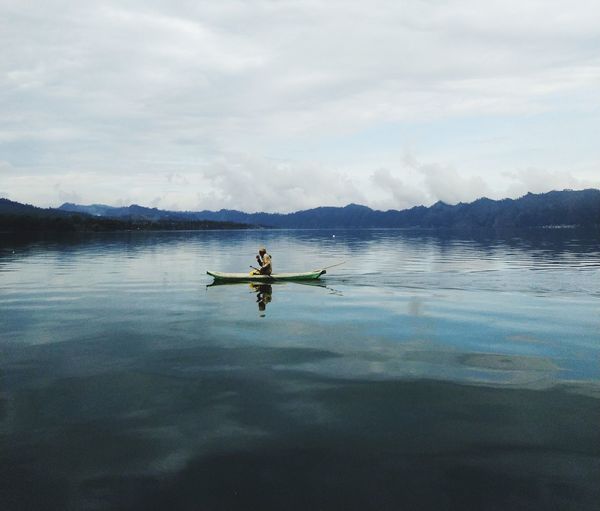 Men on boat in lake against sky