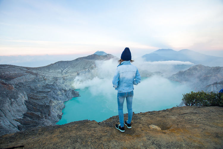 Rear view of person standing on rock against mountain