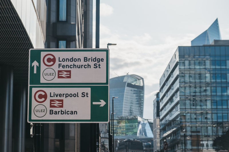 Ulez and congestion charge road sign by buildings against sky in london, uk.