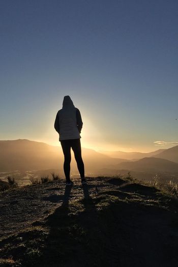 Full length of woman standing on top of mountain against sky during sunset
