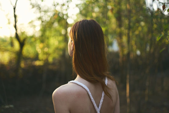 Rear view of woman standing against trees