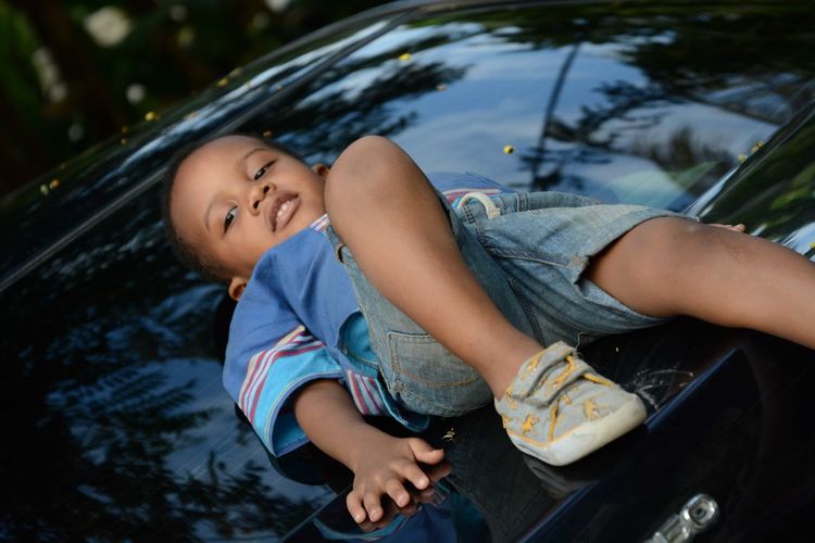 Portrait of boy lying on car