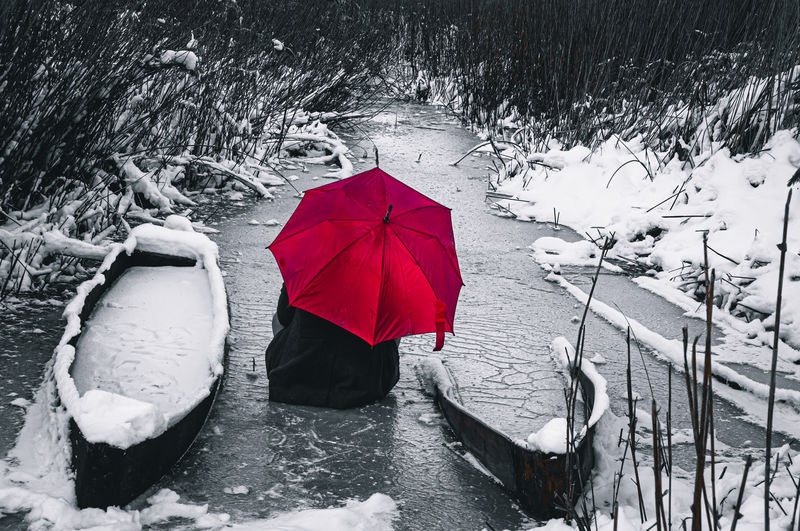 Red umbrella on snow covered landscape during rainy season
