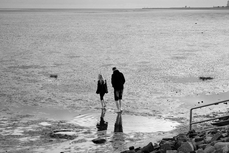 Rear view of father and daughter standing at beach