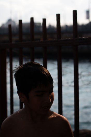 Portrait of shirtless boy standing by railing
