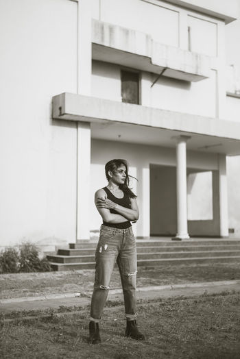Full length portrait of woman standing on field against building