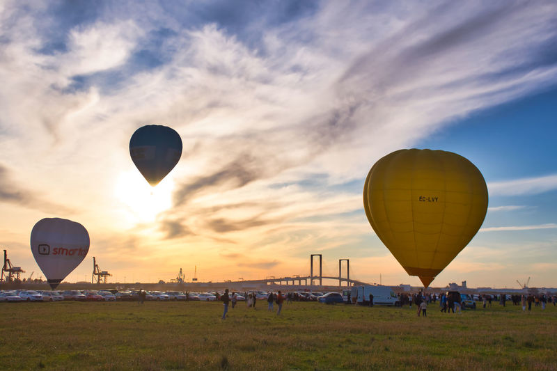 Hot air balloons flying over field against sky during sunset