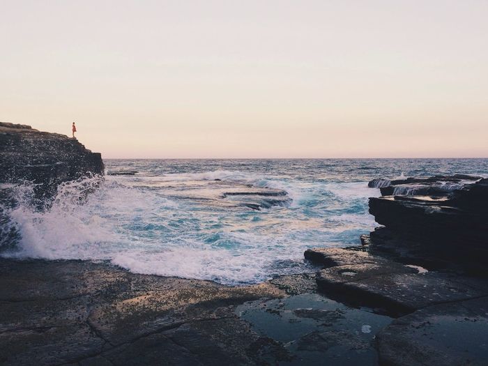 Scenic view of sea and rocks against clear sky
