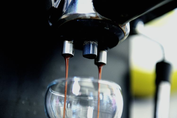 Close-up of coffee pouring in glass container from espresso maker