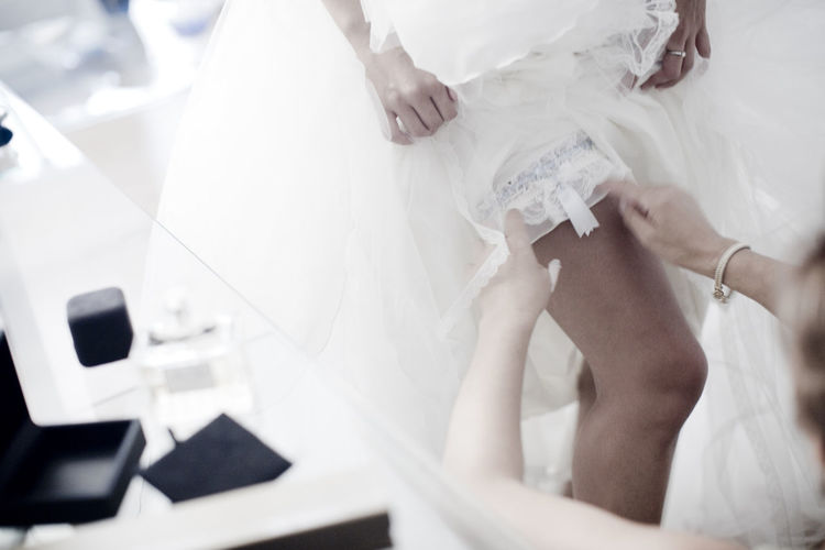 High angler view of woman assisting bride to put on garter