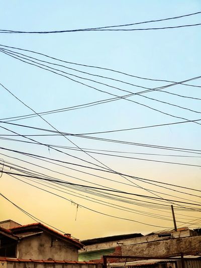 Low angle view of power cables against sky during sunset