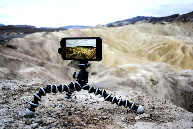 Close-up of smart phone on portable tripod on mountain