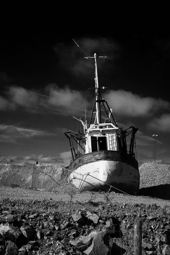 Abandoned boat moored on sea against sky