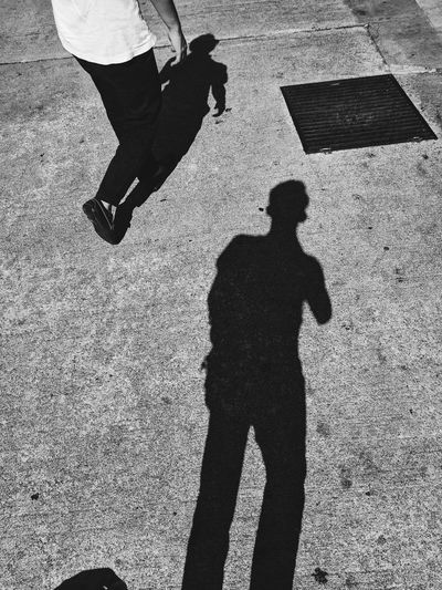 Shadow of man walking on road
