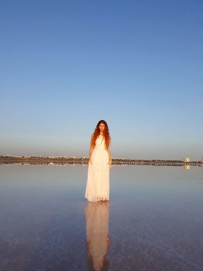 Woman standing by sea against clear sky