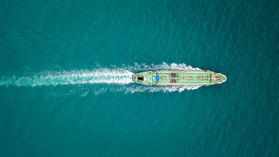 Aerial top view green oil ship tanker full speed with beautiful wave and splash water in line 