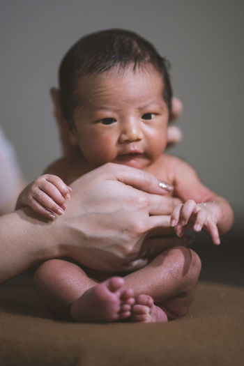 Cropped hands of mother holding cute baby boy at home