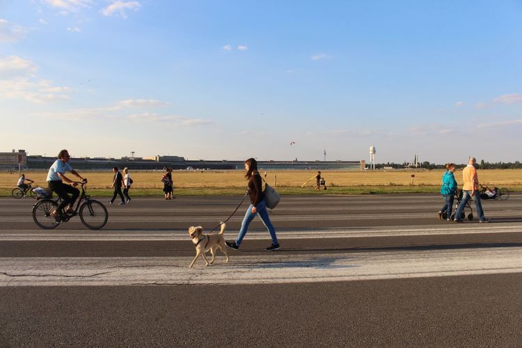 People walking on airport runway against sky