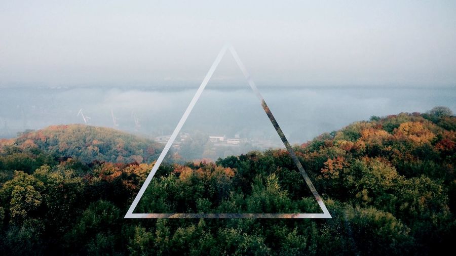 Triangle shape over forest against cloudy sky