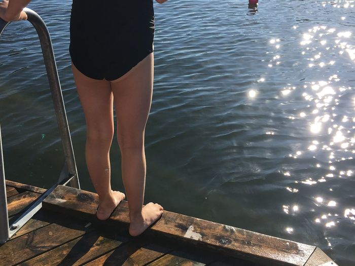 Low section of girl standing on pier 