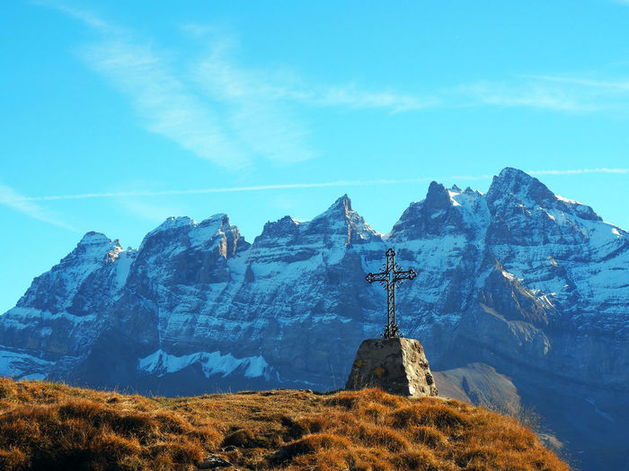 Low angle view of cross against mountain during winter