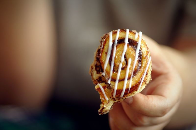 Close-up of hand holding cinnamon bun