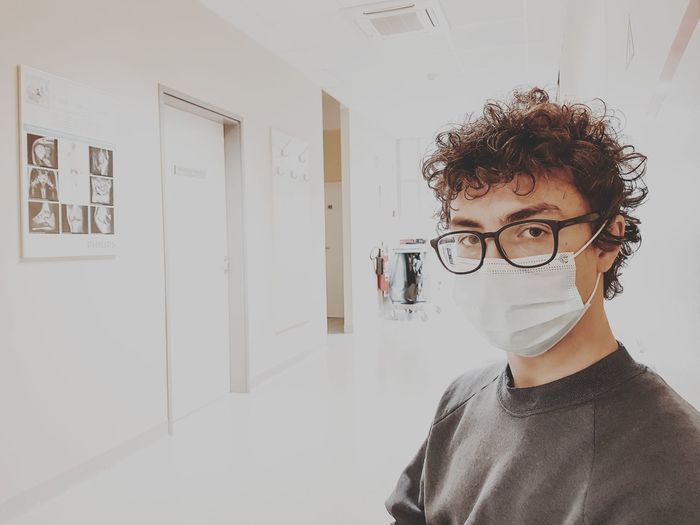 Portrait of teenage boy wearing mask standing at hospital