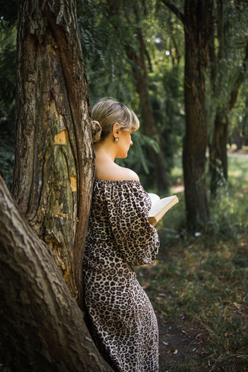 Portrait of young woman sitting on tree trunk