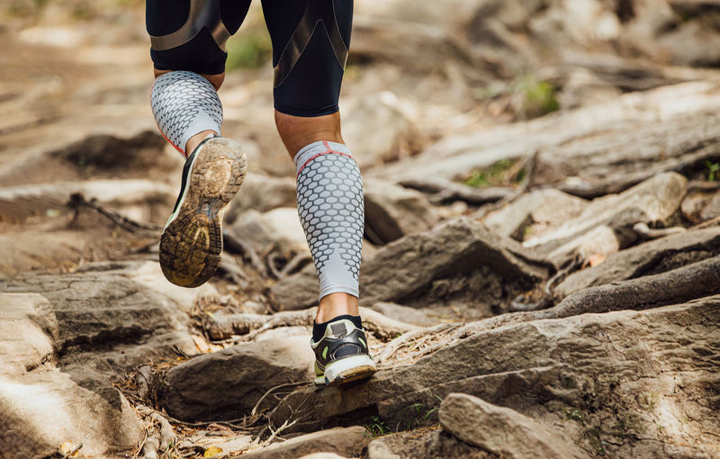 Legs male runner in compression socks run over rocks