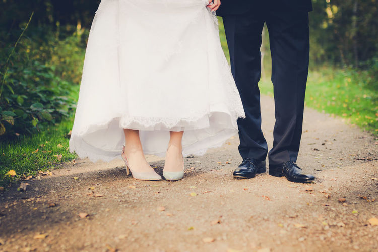 Low section of bride and groom standing on footpath