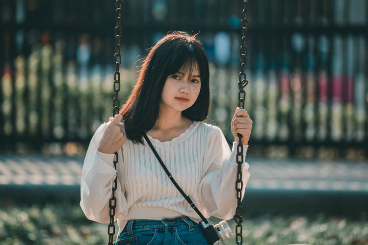 Portrait of woman standing on swing at playground