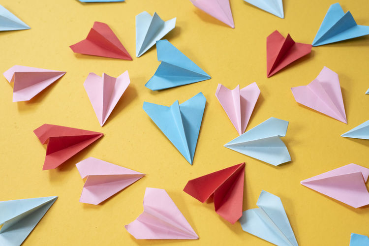 Colorful origami paper airplanes on yellow colored background