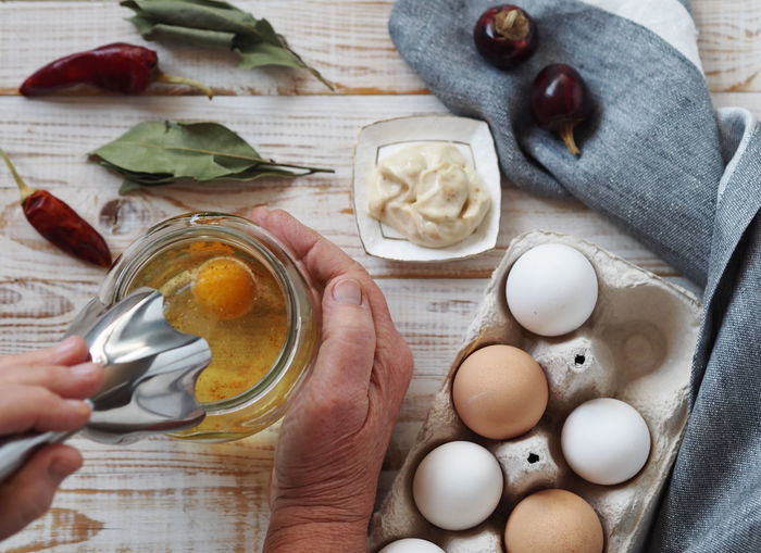 An elderly woman prepares homemade mayonnaise from natural healthy ingredients. 