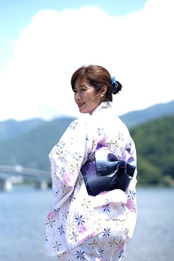 Woman wearing kimono while standing against lake