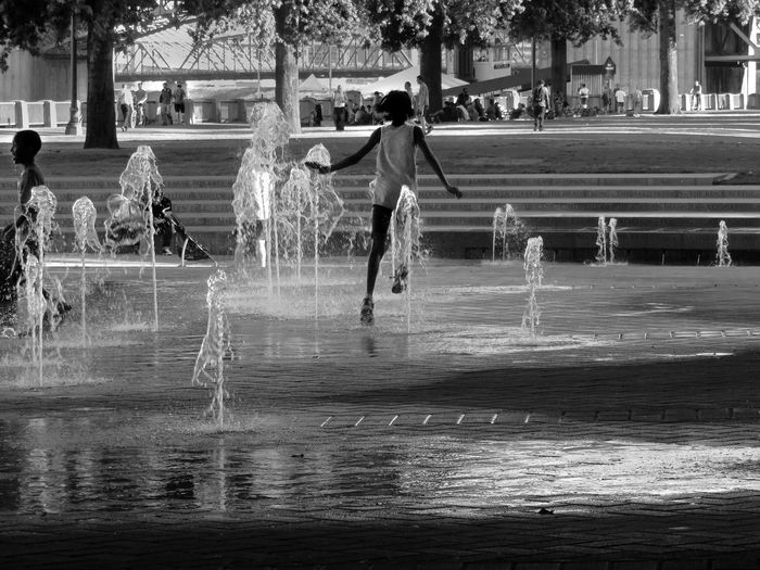Children playing amidst fountains