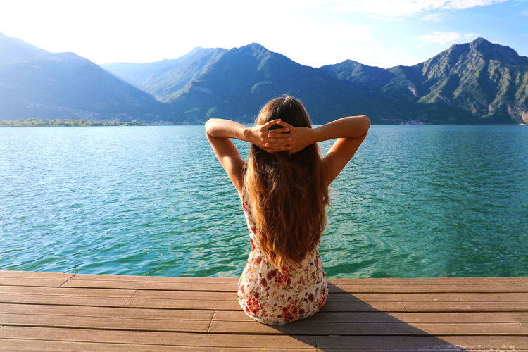 Rear view of woman looking at lake by mountains