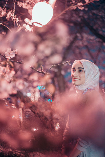 Portrait of woman standing by cherry blossom