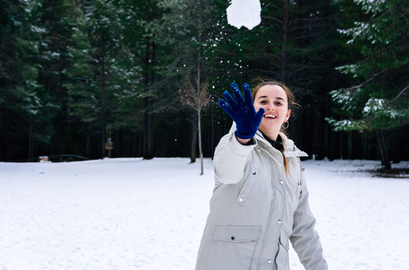 Woman throwing snowball in a natural snowy landscape.