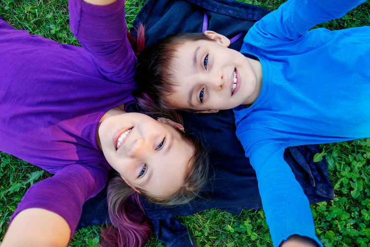 Children boy and girl belong to the grass and take a selfie, brother and sister