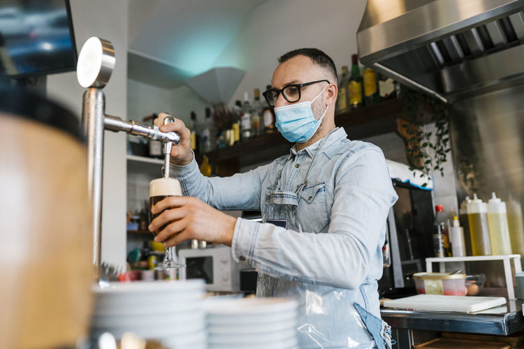 Waiter filling beer in glass in a bar during pandemic